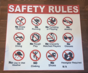 Bounce house safety rules placard listing guidelines for safe use, including no sharp objects, no rough play, and no use in wet or windy weather to ensure safe entertainment for all guests.