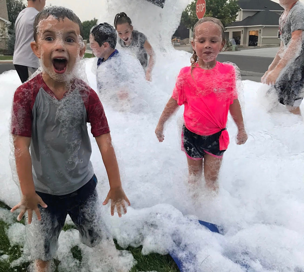 A very excited boy and girl playing in a foam party in Butler, PA, surrounded by fluffy white foam.