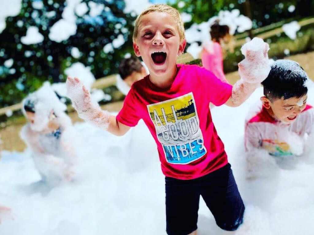 A young child joyfully playing in a bubbly foam party in McCandless Township, PA.