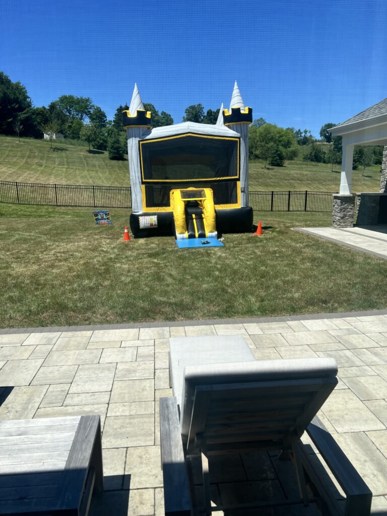 Black and yellow castle bounce house rental set up in backyard